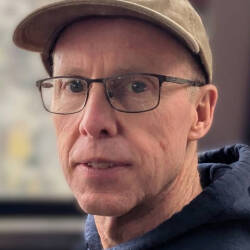 Jerry Scripps in blue hoodie and tan baseball hat, he is wearing glasses